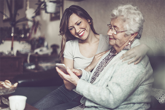 Image, mother and daughter. Mother is looking at a smartphone in her hand