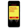 Image of the RAZ Memory Cell Phone displaying a reminder notification. The screen shows a large yellow pop-up message with bold red text that reads: "Today is your granddaughter Pamela's birthday!” Below the message is a red “Close” button for dismissing the reminder. In the background, the home screen with contact photos is slightly dimmed.