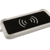 A close-up view of a white wireless charging pad for the SmartVision 3, with a black surface and a white wireless charging symbol in the center, connected to a white charging cable.